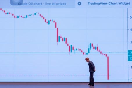 Miniature figure of a businessman standing in front of a crude oil price chart showing a sharp decline