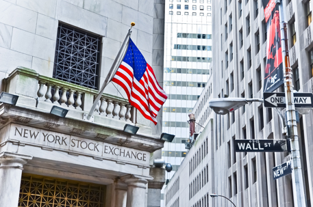 New York Stock Exchange building with American flag and Wall Street sign