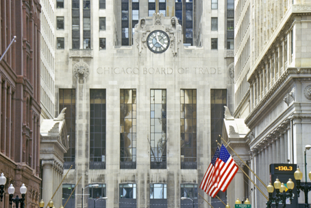 The Chicago Board of Trade building facade with its clock, carved figures, and an American flag on LaSalle Street.