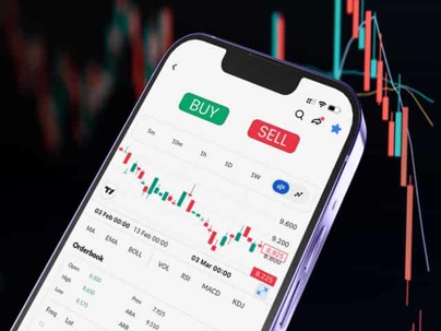 Smartphone displaying a trading app with buy and sell buttons and a candlestick chart, the kind of front-end software covered by CFTC Letter 26-25's no-action relief for passive software providers